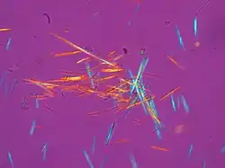 numerous multi-colored needle-shaped crystals against a purple background