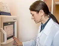 A woman views a computer screen attached to an automated analyzer which is displaying sensitivity results for a series of antibiotics.