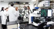 Researchers standing and discussing in a imaging facility/laboratory which is surrounded by advanced electron and various other microscopes