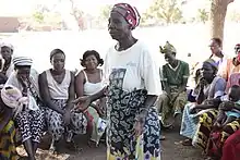 Traditional midwife in Africa at a community meeting, explaining the dangers of cutting for childbirth