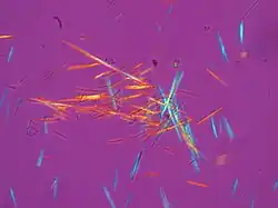 numerous multi-colored needle-shaped crystals against a purple background
