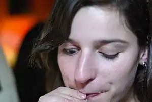 An affected young woman demonstrating the Marcus Gunn Jaw Wink Phenomenon. The woman cannot control her eyelids while sucking on a straw. This is a particularly mild case