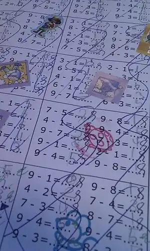 An arithmetic worksheet scribbled all over and decorated with stickers, with some numbers handwritten in pencil