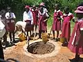School children in Zimbabwe digging a shallow pit for an Arborloo toilet (a variation of a pit latrine), Epworth in Harare, Zimbabwe.