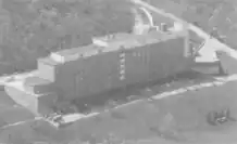 A black-and-white aerial photograph of a rectangular brick building