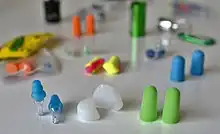 White surface with several different forms of earplugs in different colors and shapes