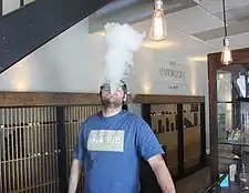 E-cigarette user blowing a cloud of vapor.