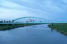 River under bridge with city in background