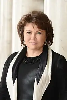 Tatyana Bakhteeva. A white woman with short brown hair and blue-gray eyes. She wears pearl earrings and a black-and-white blazer over a black blouse.