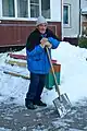 A cleaner shoveling snow off from the sidewalks.