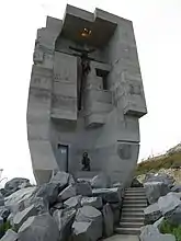 Back side of the monument, showing a weeping young woman and a damaged crucifix.