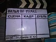 A clapperboard with a dry-erase display being used for a Russian-language film.