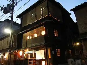 Sudare on a three-story machiya at dusk. Opaque amado shutters may soon be put up for privacy.