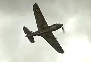Underside of single-engined monoplane in flight, with twin machine guns on each wing