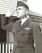 Half portrait of man in dark military uniform with forage cap, saluting