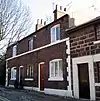 A row of brick cottages in two storeys with stone dressings and a prominent string course