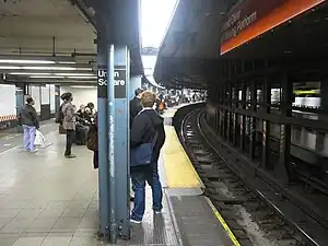 View of the downtown platform of the Lexington Avenue Line station. The local track is to the left, and the express platform is to the right. Due to the extremely sharp curve, there are gap fillers on the platforms.