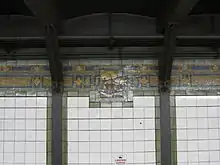 A tile mosaic on top of the outer wall of the Broadway Line platforms. The mosaic depicts the junction of Broadway and Bowery Road in 1828.