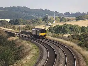 A two-car train passing alongside fields