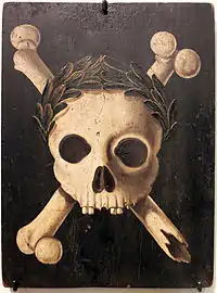 A painting of a skull wearing a wreath on its forehead, with broken crossbones behind it