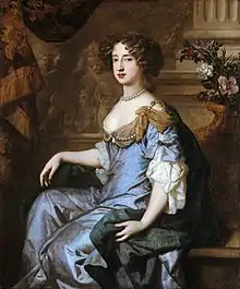 Formal seated portrait of Mary. She wears a grey satin decollatage dress and a blue satin cloak with gold swathes at her shoulders. Her hair is formally arranged in curls and she wears a necklace of large grey pearls.