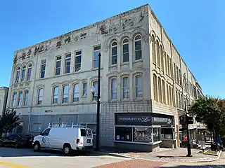 The livery stable and mixed retail block was built between 1904 and 1910 with Italianate arched parapet over the entrance to the former stable and another set of Baroque parapets.