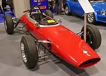 Red open cockpit single seat race car with unguarded tyres