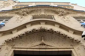 Peacocks and motifs inspired by their feathers (and sometimes other animals) – Relief above the door of Rue Octave-Feuillet (Paris) no. 19 in Paris, by Maurice Du Bois d’Auberville (1910)