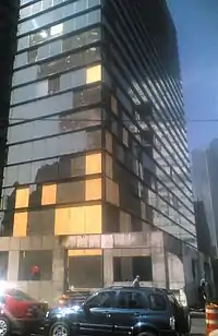 Corner of glass office building with several windows boarded up