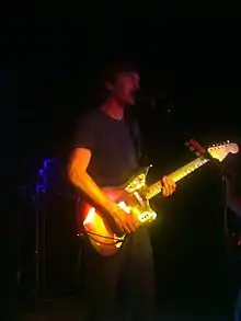 A man playing a guitar and singing into a microphone