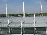view from above of the roof of a curved roof of a building with tall white poles and various cables connecting them