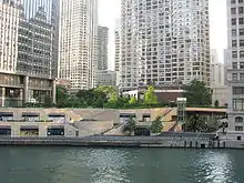 a riverwalk and park next to a river bank surrounded by buildings