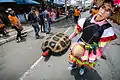 A lady drags a turtle with a phallic head behind her on the day of the parade