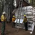 Resource Advisors (READ) from the National Park Service apply fire-resistant wrap to a historic Bildeo cabin.