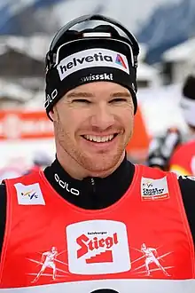 A smiling man with black clothes and a red bib