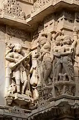 Sculptures on wall. Instrument resembling Rudra veena, far left.