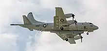 A P-3C Orion flying in landing configuration with the LSRS, which is a large pod mounted on its belly.