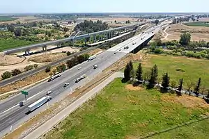 The same viaduct completed in April 2021. Adjacent are the SR-99 freeway and, between them, a single-track railroad line which is used for freight.