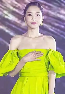 Naeun wearing a long green gown holding her chest in December 2021