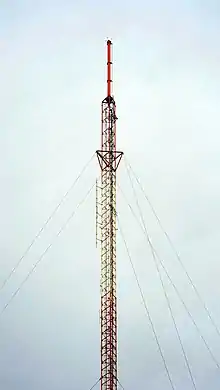 A red-and-white tower topped by a red cylindrical antenna