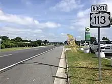 A four-lane asphalt divided highway in an area of businesses