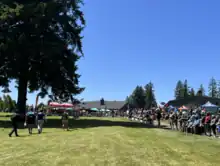 A large gallery watches as the players walk up the fairway to the 18th green at the 2023 Portland Open