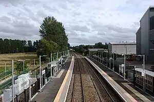 Looking along two railway tracks with platforms on either side and a large building to the right