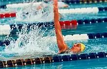 A woman swims the backstroke between two lanes in a swimming pool.