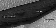 Close view of wall of triangular depression, as seen by HiRISE  layers are visible in the wall. The lower layers are tilted, while layers near the surface are more or less horizontal. Such an arrangement of layers is called an  "angular unconformity."