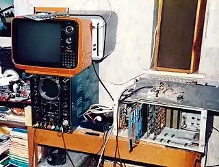 An open frame newbear 77-68 shown next to an oscilloscope with a portable television on top.
