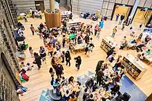 A bird's eye photograph of a brightly lit children's library space full of children doing craft activities