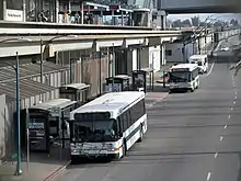 City buses next to an elevated rapid transit station