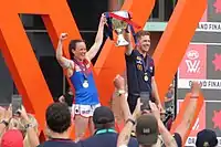 Pearce holding a large trophy alongside her coach