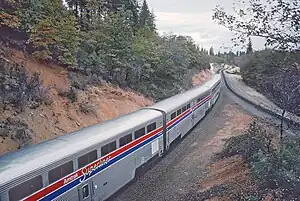 Silver railcars next to a hill